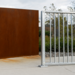 Weathering steel wall with rust patina beside a bright galvanized steel railing